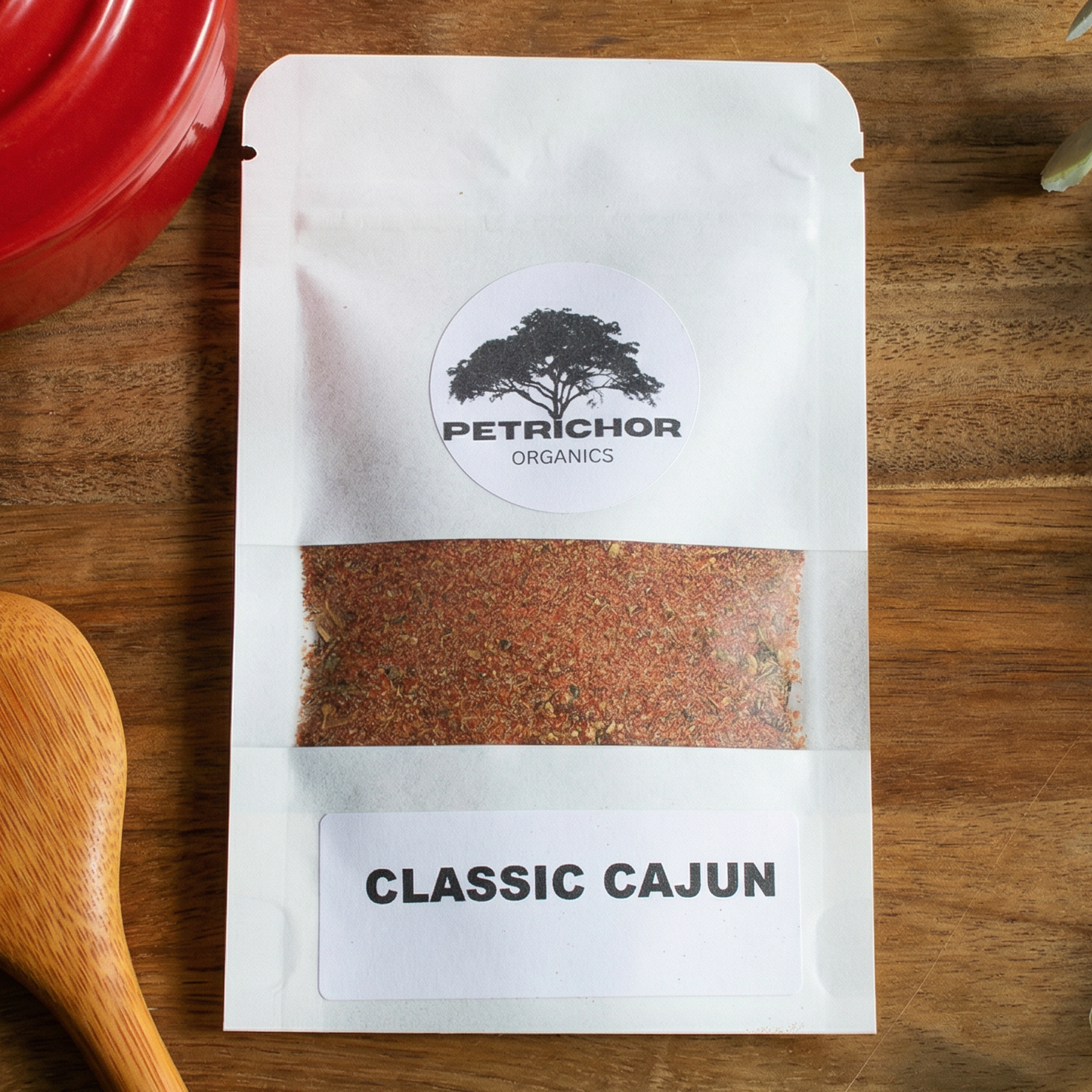 Petrichor Classic Cajun seasoning packet on a wooden surface with a red pot and wooden spoon.